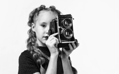 Ateş et. Retro kamera. Mutlu çocukluk. Çocuğun şık bir görünüşü var. Modern hayatta fotoğrafçılık. Eski moda fotoğraf makinesi olan çocuk beyaza izole edilmiş. Eski teknoloji. Genç kız fotoğraf çekiyor..