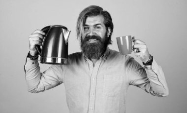 Olgun sakallı adam gündelik moda gibi görünüyor. Çaydanlık, cihaz..