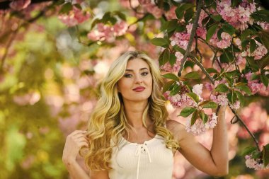 Çiçeklerin kadınları neden her zaman mutlu ettiğini. Mutlu bahar günleri. Kız bahçede sakura çiçeğinin tadını çıkarıyor. Bahar çiçeği açan ağaç. Kiraz ağacı. Çiçek aroması. Uyum ve kadın enerjisi. Bahar sembolü.