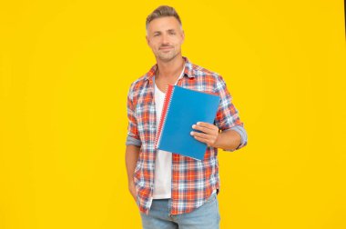 Eğitim için okul kitaplarını tutan mutlu öğretmen sarı arkaplan, kopyalama alanı.