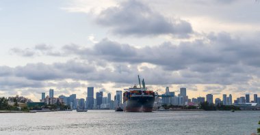 Kargo gemisi limandan ayrılıyor. Kargo işi. Konteyner gemisi. Nakliye lojistiği. Miami ufuk çizgisinde konteynırlı bir kargo gemisi. Konteynır Miami Skyline, Florida 'da kargo gemisine yüklendi..