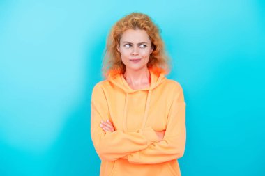 Sıradan kapüşonlu, şık, beyaz bir kadın. Modayla ilgilenen kız modaya uygun ve parlak görünüyor. Mavi üzerine kapüşonlu giyen kadın. Moda modeli. Şık kapüşonlu kızıl saçlı kız. Kapüşonlu kazak.