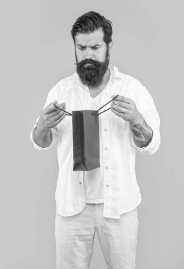 Arka planda alışveriş yapan meraklı adam. Alışveriş çantasındaki alışveriş yapan adamın fotoğrafı. Alışverişte çalışan adam sarıyı soyutlamış. Stüdyoda alışveriş yapan adam..