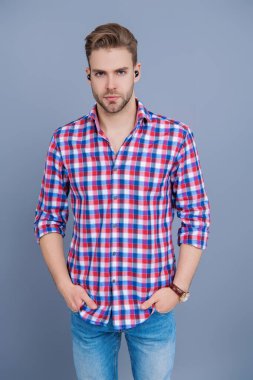 Kablosuz kulaklık cihazı. Aleti olan bir milenyum adamı. Kablosuz kulaklıklı bir adam. Adam gri üzerinde kulaklık kullanıyor. Modern kablosuz kulaklıklar. Elsiz kulaklık. Kulaklık cihazı aksesuarı. Kablosuz kulaklıklar..