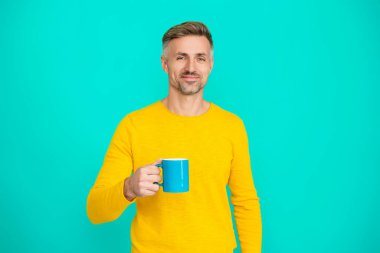 Sabah kahvesi vakti. Yaşam tarzı konsepti. Espresso içiyorum. Çay içen adam. Sıcak bir sabah. Evde kahve molası. Maviye izole edilmiş kahve fincanı olan olgun bir adam. Şerefe..