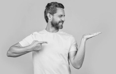 Reklam sunan pozitif adam sarı alanda izole edilmiş, kopyalama alanı. Adam arka planda reklam sunuyor. Stüdyoda reklam sunan adam. Reklam sunan adamın fotoğrafı.