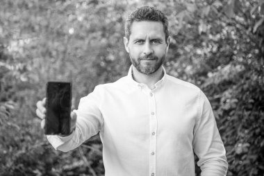 Uygulama gösteren iş adamlarının seçici odağı. İş adamı uygulamayı açık havada gösteriyor. İş adamı telefonda uygulama gösteriyor. Uygulamayı kopyalama alanı ile gösteren iş adamının fotoğrafı.