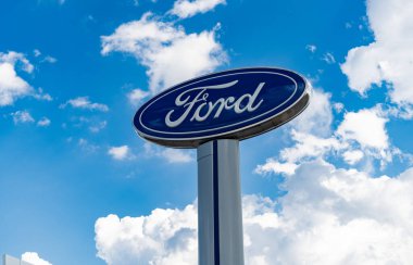 Chicago, ABD - 17 Ağustos 2024: Ford logosu mavi bulutlu gökyüzüne karşı. Ford motor şirketi en eski araba şirketidir. Bayiliğin yanındaki Ford tabelası