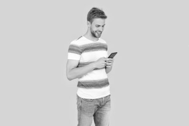 Gülümseyen adamın telefon iletişimi var. Telefonlu bir adamın dijital iletişimi. Adam mesajlaşmak ya da mesaj atmak için telefonunu kullanıyor. Adam etkili iletişim kurmak için telefonu kullanıyor..