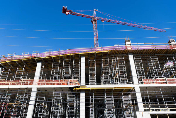 Building and construction. Hoisting crane. Construction at building site with crane. Construction crane at building area. Construction site with building crane. Industrial area. Site inspection.