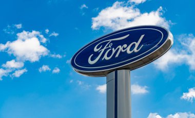 Chicago, ABD - 17 Ağustos 2024: Ford logosu mavi bulutlu gökyüzüne karşı. Ford motor şirketi en eski araba şirketidir. Bayiliğin yanındaki Ford tabelası