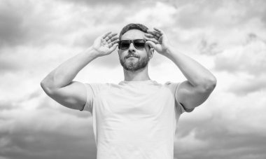 Gökyüzünde sarı gömlekli ve güneş gözlüklü bir adamın yüzü..