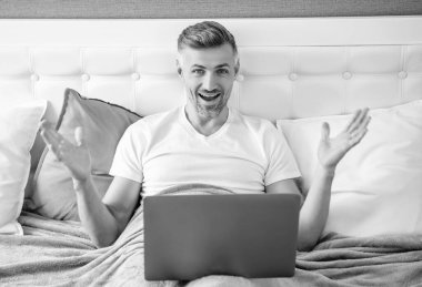 Yatakta dizüstü bilgisayarda çalışan olgun bir adam..