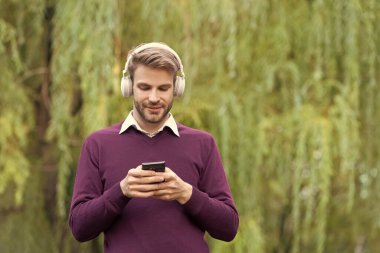 Genç neşeli adam kulaklıkla müzik dinliyor ve dışarıda telefonla konuşuyor..