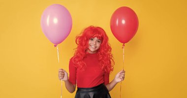 Sarı arka planda parti balonu olan neşeli genç çocuk..