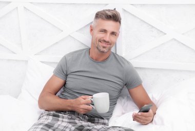 photo of happy man messaging in morning at home. man messaging in morning. man messaging in morning in bed. man messaging in morning in bedroom.