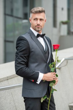 Siyah smokinli zarif adam. Smokin giymiş, papyonlu bir adam. Kırmızı güllü beyaz smokinli adam..