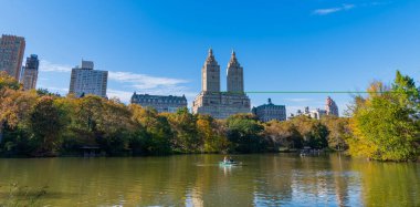 New York City, ABD - 25 Ekim 2023: sonbahar manzarası. Central Park 'ta kürek çeken insanlar. Sonbahar ağaçlı Central Park. Sonbahar manzarası. Gölde teknesi olan New York Şehri Central Park.