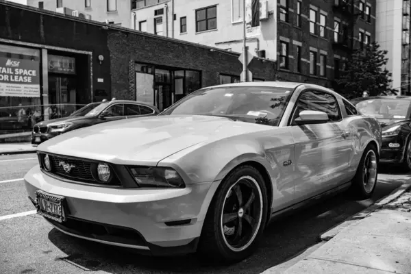 New York, ABD - 05 Ağustos 2023: 2011 Ford Mustang V6 sarı araba önü ve sürücü tarafı manzaralı, park edilmiş.