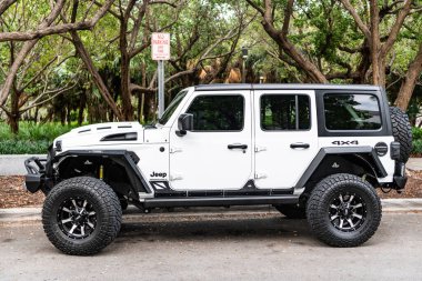 Miami Beach, Florida USA - 10 Haziran 2018 Jeep Wrangler Sınırsız Sahara 4x4 beyaz okyanus sürücüsü Miami plajı. Jeep yaygın bir arazi aracı markasıdır. Yan görünüş. beyaz.