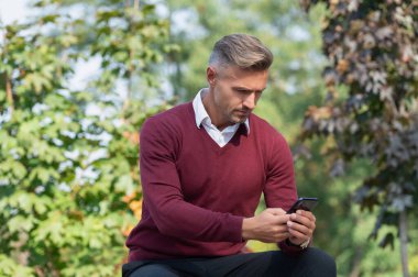 İnternet işi. İşadamı sonbaharda telefon kullanır. Sonbahar adamı telefonu kullanır. Sıradan bir iş adamı gibi. İş adamı dışarıda telefonla mesajlaşıyor. İş iletişimi tarzı. Çevik iş.