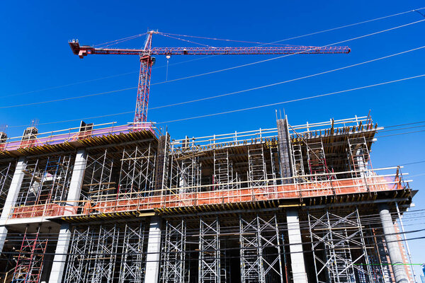 Construction crane at building area. Construction site with building crane. Industrial area. Building and construction. Hoisting crane. Construction at building site with crane.