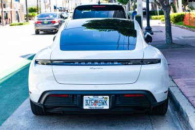 Miami Beach, Florida USA - 9 Haziran 2024 Miami plajında Porsche Taycan beyaz rengi. Ocean 'daki lüks araba porshche' si Miami plajına gidiyor. ön köşe görünümü