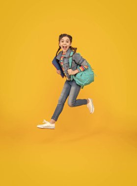 Okul, sarı arka planda atlayan enerjik kız. Havada bağıran heyecanlı liseli kız. Okul eğitimi. Okula geri dön..