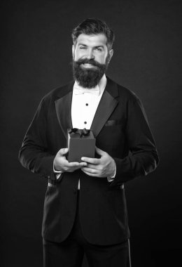 Smokinli mutlu adam siyah arka planda papyon takıyor ve erkekler günü için bir kutu hazırlıyor..