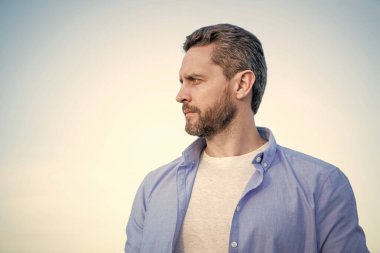 pensive man portrait standing peaceful. pensive man in shirt outdoor. pensive man on sky background.