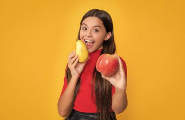 cheerful amazed child hold fresh apple and pear on yellow background. selective focus.