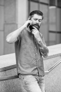 Düşünen adam dışarıda akıllı telefondan konuşuyor. Adam sokakta akıllı telefondan konuşuyor. Akıllı telefondan konuşan bir adamın fotoğrafı. Adam dışarıda akıllı telefondan konuşuyor..