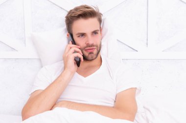 Yatakta akıllı telefonu olan bir adam. Akıllı telefon iletişimi. Milenyum adamı yatak odasında akıllı telefon kullanır. Hastalık izni iste. Yatakta telefonla konuşan genç bir adam. Telefon var. Gadget bağımlılığı.