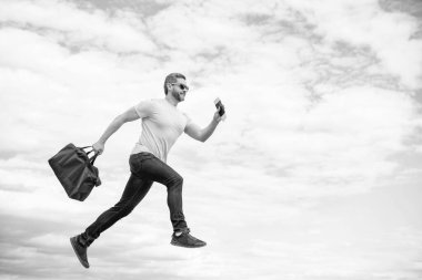 Seyahat çantasıyla çalışan enerjik bir adam gökyüzü arkaplanı, kopyalama alanı.