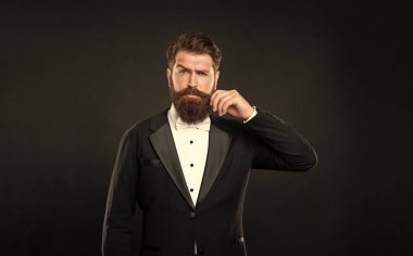 serious man in tuxedo bow tie with moustache. man in formalwear on black background. male formal fashion.