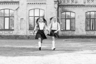 two teen kids in uniform walking together outdoor.