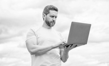 Bilgisayarda çalışan bir adam gökyüzü arka planında. iş çevrimiçi.