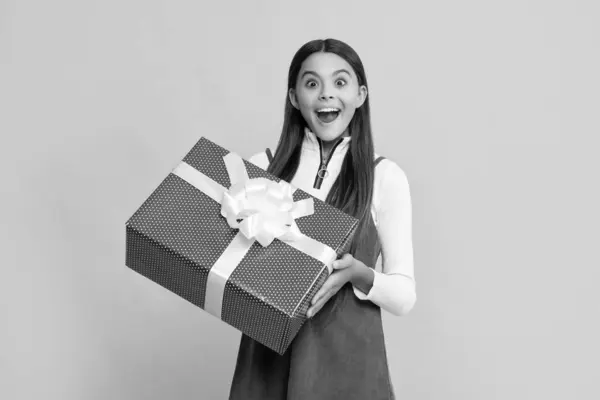 stock image happy amazed child with present box on yellow background.