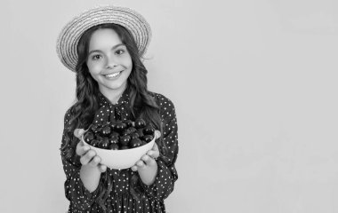 happy teen child hold cherry bowl on yellow background.