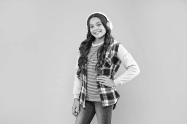 smiling teen girl wearing headphones on pink background, modern life.