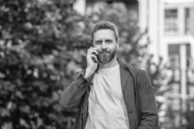Neşeli adam dışarıdaki akıllı telefondan arıyor. Adamın fotoğrafı. Akıllı telefondan ara ve konuş. Adamın dışarıda akıllı telefonları var. Adam sokakta akıllı telefon görüşmesi yapıyor..
