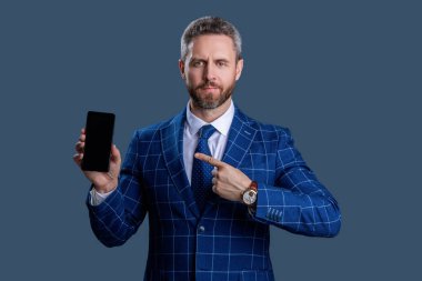 Takım elbiseli adam. Yeni telefon uygulaması. Ürünü sunuyorum. İş uygulamasının reklamı. İspanyol iş adamı telefon ekranını sunuyor. Griler 'de izole edilmiş bir telefon gösteren bir iş adamı. Bunu dene..