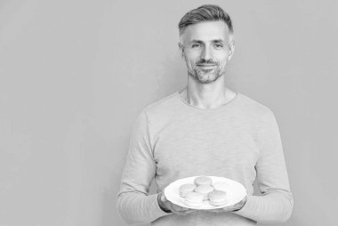 Erkekler leziz badem kurabiyelerini mavi renkte izole eder. Kopya uzayı. Stüdyoda nefis kurabiyeler var. Adam arka planda lezzetli bir badem kurabiyesi tutuyor. Erkek fotoğrafı. Nefis kurabiyeler..