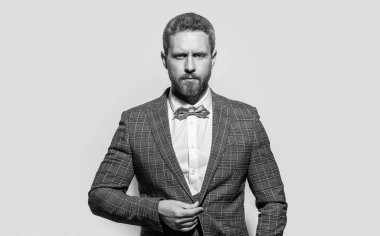 Smokin giyen bir adamın portresi. Smokinli adam gri arka planda izole edilmiş. Stüdyodaki smokinli adam. Smokin giyen adamın fotoğrafı..