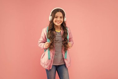 Çocukluk gelişimi. Modern kulaklıklı, sırt çantalı bir çocuk. Online eğitim. Okula dönüyorum. Kulaklık takan genç bir kız. Müzik dinle. Kablosuz kulaklık cihazı aksesuarı. yeni teknoloji.
