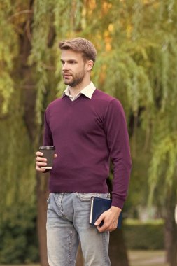 Genç yakışıklı adam sabah kahvesini dışarıda içiyor..