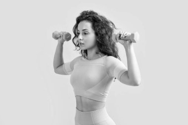 Fitness kadını stüdyoda halter egzersizi yapıyor. Fitness kadınları halter egzersizlerini sarı arka planda izole ederler. fitness ve spor.