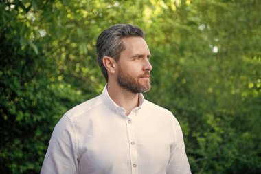 Handsome professional guy in white shirt looking aside natural background.