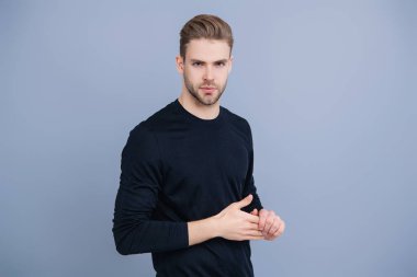 Beyazlı genç bir adam gri yolda izole edilmiş. Kendine güvenen adam portresi. Erkeklerin cilt bakımı. Erkek derisi. Adamın şık bir saç kesimi var. Moda saç stili olan bir adam. Sıradan erkek tarzı. Gençlik Parlaklığı.