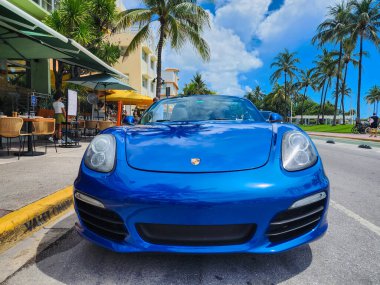 Miami Beach, Florida USA - 8 Haziran 2024: 2018 Porsche 718 Boxter mavisi Miami sahilinde. Ocean 'daki lüks araba porshche' si Miami plajına gidiyor. ön görünüm